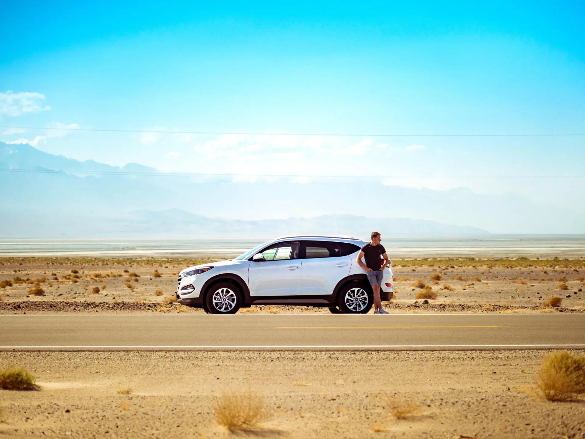 A white SUV parked along an open desert highway in Arizona.