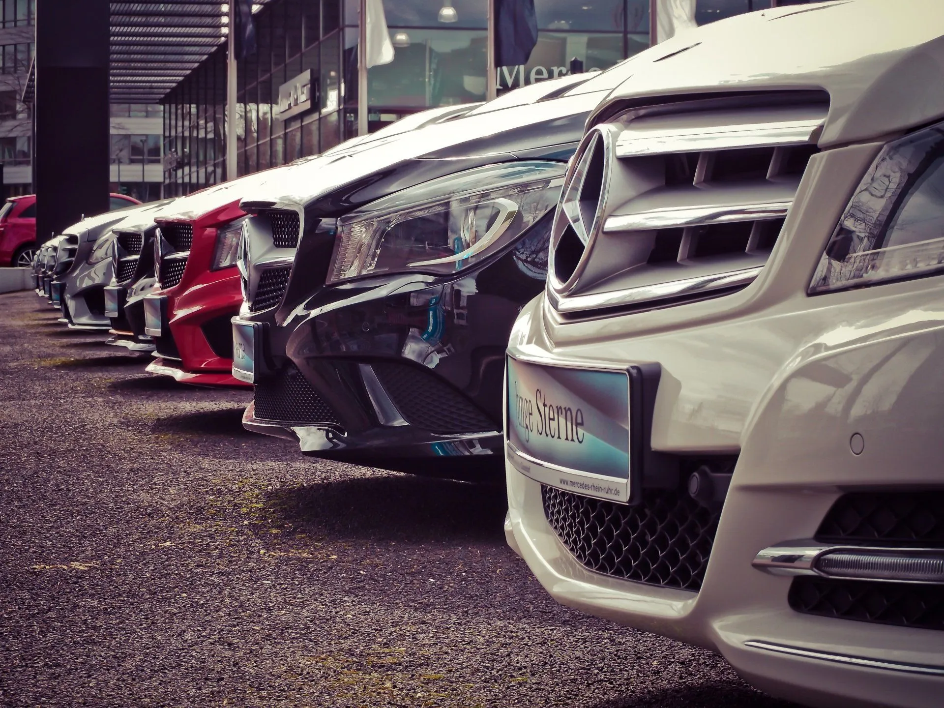 A row of cars lined up front-to-back on a dealership lot.