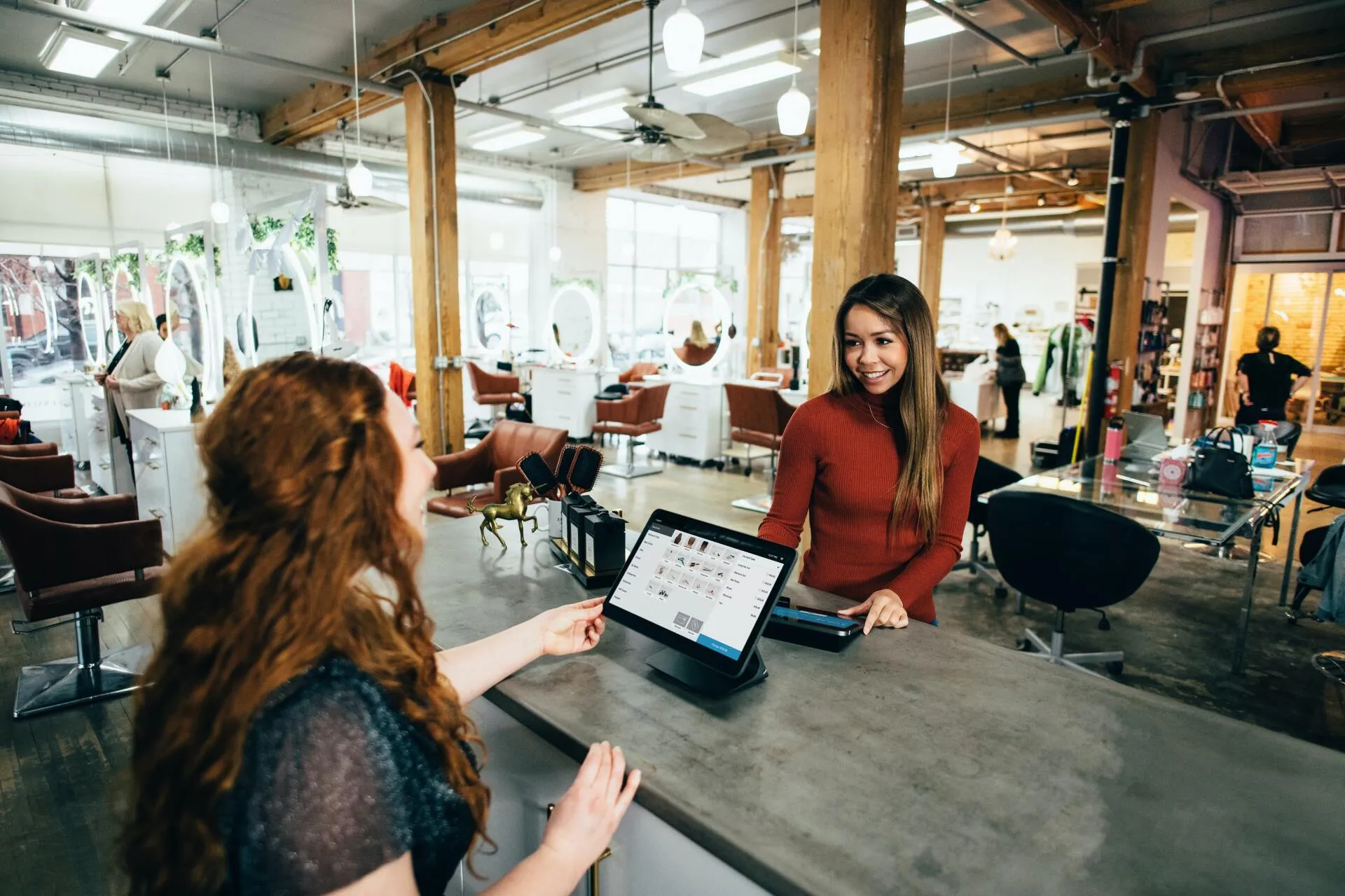 A stylist helping a customer at the front counter of a small salon business.